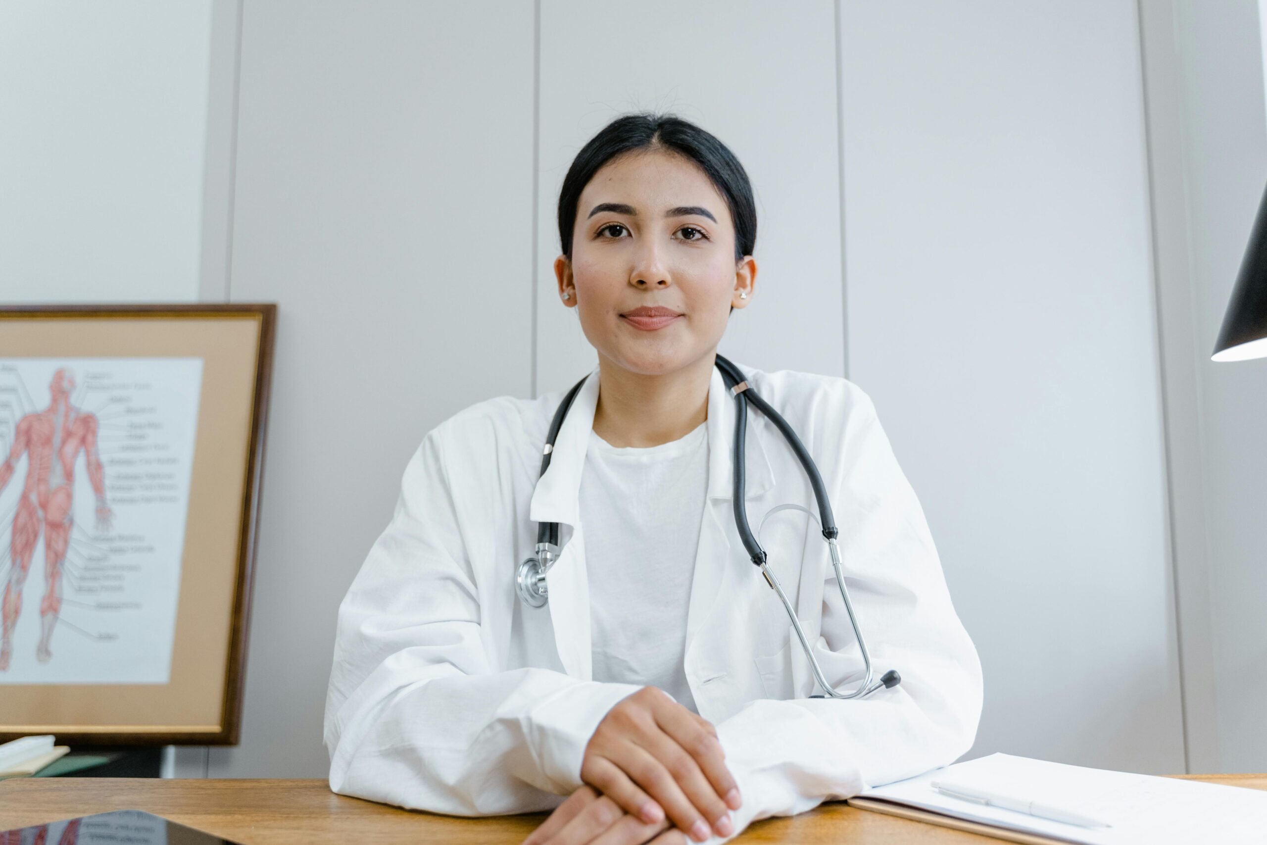 A new nurse practitioner sits thoughtfully alone at a desk, reflecting on early career challenges.